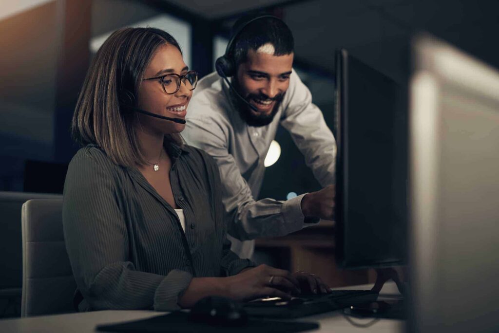 shot of two call centre agents working together in an office at night